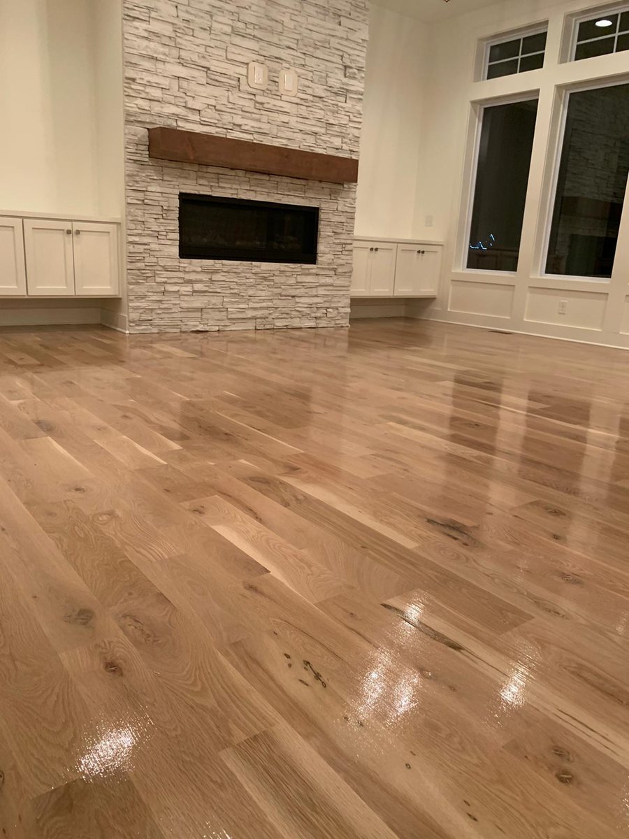Light hardwood floor in a finished room with a stone fireplace